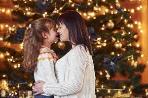 mère embrassant sa petite fille dans une chambre décorée de noël photo