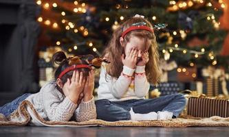 deux petites filles s'amusent dans une chambre décorée de noël avec des coffrets cadeaux photo