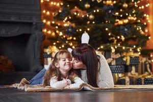 petite fille et sa mère allongées sur le sol ensemble dans la salle décorée de noël photo