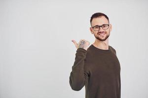 jeune homme à lunettes de soleil debout à l'intérieur sur fond blanc photo