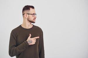 jeune homme à lunettes de soleil debout à l'intérieur sur fond blanc photo