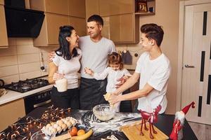 une famille heureuse s'amuse dans la cuisine et prépare de la nourriture photo