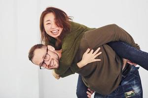 heureux couple multiethnique dans des vêtements décontractés s'amuser ensemble à l'intérieur dans le studio. mec caucasien avec petite amie asiatique photo