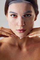 portrait de femme est en studio sur fond blanc avec masque de beauté sur le visage photo