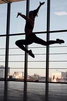 silhouette de jeune femme sportive en vêtements de sport qui fait des tours acrobatiques dans la salle de gym photo