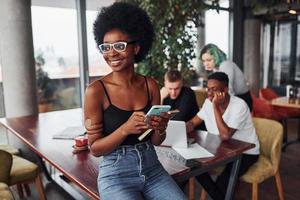 femme noire debout devant un groupe de personnes multiethniques avec une fille alternative aux cheveux verts travaille ensemble près de la table à l'intérieur photo