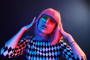 portrait de jeune fille aux cheveux blonds à lunettes en néon rouge et bleu en studio photo