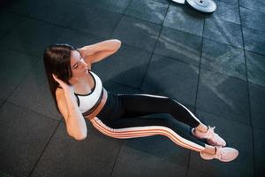 jeune femme en vêtements sportifs faisant des abdominaux sur le sol dans la salle de sport photo