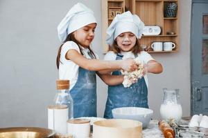 deux petites filles en uniforme de chef bleu préparant la nourriture dans la cuisine photo