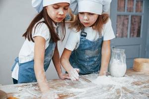 deux petites filles en uniforme de chef bleu préparant la nourriture dans la cuisine photo