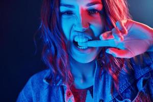 portrait de jeune fille aux cheveux bouclés en néon rouge et bleu en studio photo
