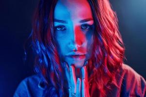 portrait de jeune fille aux cheveux bouclés en néon rouge et bleu en studio photo