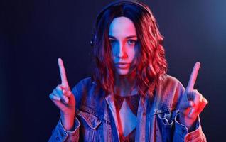 portrait de jeune fille qui écoute de la musique dans des écouteurs en néon rouge et bleu en studio photo