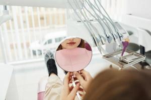 regarde le miroir. petite fille visitant un dentiste en clinique. conception de la stomatologie photo