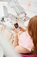 regardant le portrait de la femme dans le smartphone petite fille visitant le dentiste à la clinique. conception de la stomatologie photo