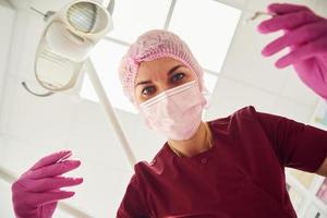 jeune femme dentiste en masque de protection travaillant dans une clinique de stomatologie. vue à la première personne photo