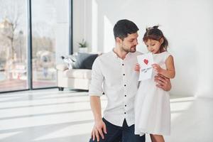 joyeuse fête des Pères. fille fait une surprise pour papa en donnant une carte postale avec coeur photo