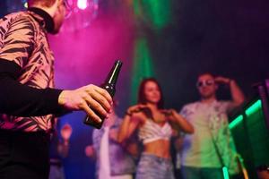 faire la fête avec de l'alcool. les jeunes s'amusent dans une boîte de nuit avec des lumières laser colorées photo