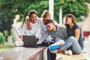 concentré au travail. avec ordinateur portable. groupe de jeunes étudiants en vêtements décontractés dans la ville pendant la journée photo