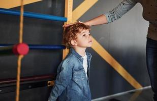 enseignant mesurant la taille de l'enfant à l'intérieur à la maternelle photo