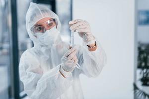 détient des tubes à essai. portrait d'une femme médecin scientifique en blouse de laboratoire, lunettes défensives et masque photo