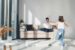 père heureux avec sa fille passant du temps libre avec un ordinateur portable à la maison ensemble photo