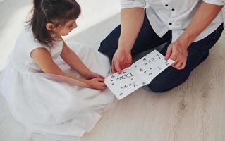 joyeuse fête des Pères. fille fait une surprise pour papa en donnant une carte postale avec coeur photo