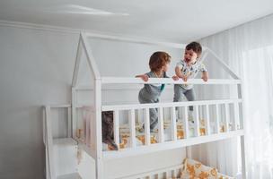 deux petits garçons se reposent et s'amusent ensemble dans la chambre à coucher. chat assis près d'eux photo