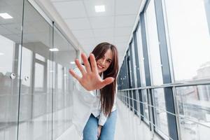 brune en chemise blanche à l'intérieur dans un aéroport moderne ou un couloir pendant la journée photo