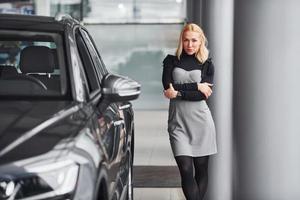 belle blonde en vêtements élégants debout près de la nouvelle voiture moderne photo