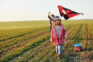 deux petites amies s'amusent avec un cerf-volant et une petite voiture sur le terrain à la journée ensoleillée photo