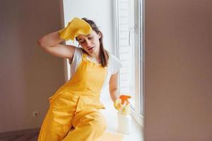 femme au foyer fatiguée en uniforme jaune prend une pause à l'intérieur. conception de rénovation de maison photo