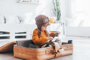 les petits garçons en costume de pilote rétro s'amusent et s'assoient dans une valise à l'intérieur pendant la journée photo