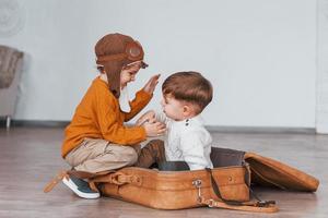 deux petits garçons s'amusent et s'assoient dans une valise à l'intérieur pendant la journée photo