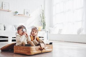 deux petits garçons s'amusent et s'assoient dans une valise à l'intérieur pendant la journée photo