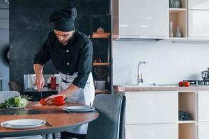 jeune chef cuisinier professionnel en uniforme faisant de la salade dans la cuisine photo