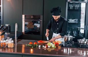 jeune chef cuisinier professionnel en uniforme travaillant dans la cuisine photo