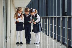 écoliers en uniforme avec téléphone dans le couloir. conception de l'éducation photo