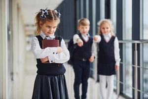 petite fille se fait intimider. conception du harcèlement. écoliers en uniforme ensemble dans le couloir photo