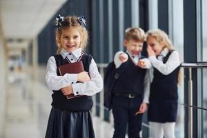 petite fille se fait intimider. conception du harcèlement. écoliers en uniforme ensemble dans le couloir photo