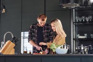 jeune couple en vêtements décontractés debout ensemble dans la cuisine et préparer la nourriture photo