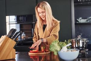 belle blonde debout à l'intérieur dans la cuisine et la préparation des aliments photo