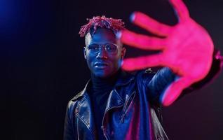 s'amuser. éclairage néon futuriste. jeune homme afro-américain dans le studio photo