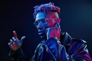 écouter de la musique. éclairage néon futuriste. jeune homme afro-américain dans le studio photo