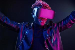 expérience de réalité virtuelle. éclairage néon futuriste. jeune homme afro-américain dans le studio photo