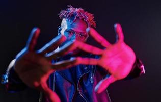 s'amuser. éclairage néon futuriste. jeune homme afro-américain dans le studio photo