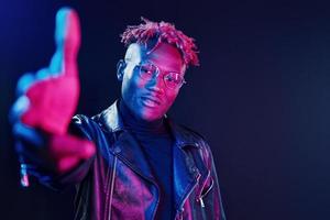 s'amuser. éclairage néon futuriste. jeune homme afro-américain dans le studio photo