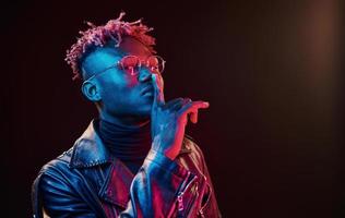 dans des verres. éclairage néon futuriste. jeune homme afro-américain dans le studio photo