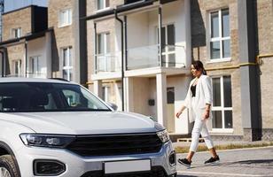 mère avec sa fille en uniforme scolaire à l'extérieur près d'une voiture blanche photo