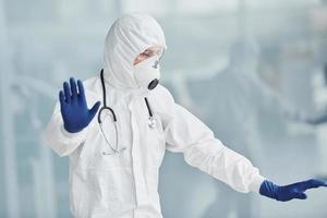 montre le geste d'arrêt à la main. homme médecin scientifique en blouse de laboratoire, lunettes défensives et masque photo